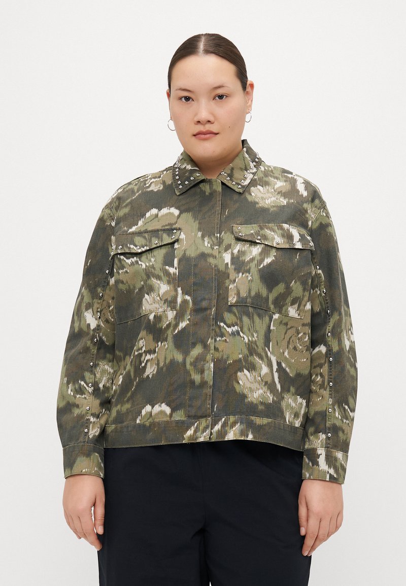 Chaqueta corta con estampado floral verde y tachuelas plateadas en el cuello y los bolsillos. Fabricada con tejido texturizado y de mangas largas.