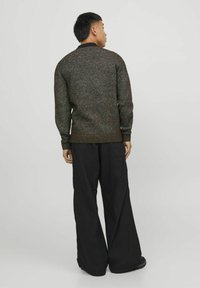 Suéter de manga larga en tejido multicolor con un acabado texturizado, combinado con pantalones amplios negros. Presenta un cuello y puños de canalé negros.