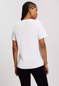 Biała bawełniana koszulka z krótkim rękawem, luźny krój i okrągły dekolt. Minimalistyczny design, gładka faktura oraz brak widocznych logo lub wzorów.