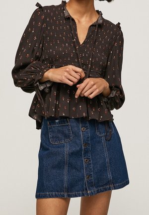 Bruine blouse met bloemenpatroon, met een geplooid ontwerp en ruches, gecombineerd met een blauwe spijkerrok met een knoopsluiting aan de voorkant.