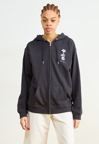 Tamno siva zip-up majica od mješavine pamuka, s kenguruda džepom, podesivim kapuljačom s vezicom i cvjetnim vezom na lijevoj strani prsiju.