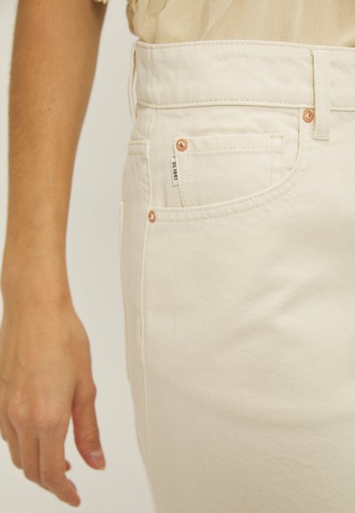 Beige värven denim jeansit, joissa on korkea vyötärö, kuparinväriset yksityiskohdat, sivutaskut ja teksturoitu kangaspinta.