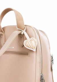 Béžová kožená kabelka se strukturovaným popruhem, stříbrným kováním, boční kapsou na zip a přívěskem ve tvaru srdce s logem v světlých barvách.
