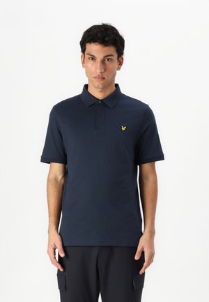 Polo marine en coton, doté d'un col à deux boutons et d'un accent logo jaune sur la poitrine gauche. Manches courtes et coupe classique.