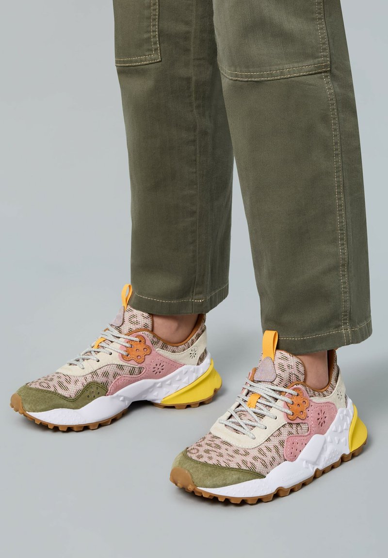 Baskets multicolores avec un upper texturé crème, rose et vert, des accents oranges et une semelle en caoutchouc jaune présentant un motif de profondeur rugueuse.