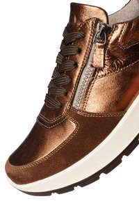 Baskets métalliques marron avec de grands lacets marron, fermeture éclair latérale, semelle épaisse blanche et détails en daim sur l'avant et les côtés.