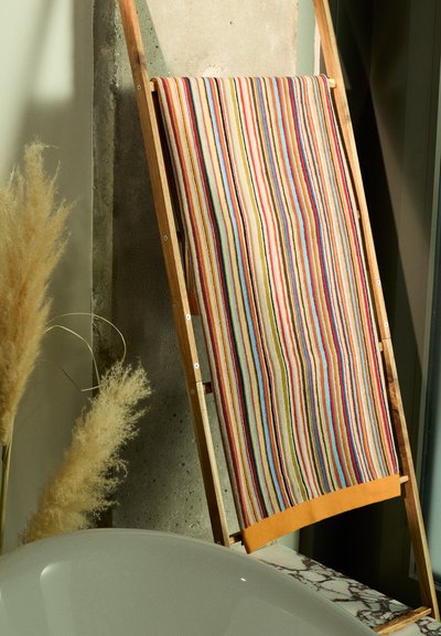 Multicolored striped towel on a wooden ladder, featuring horizontal stripes in red, blue, yellow, and green, with a solid orange bottom.
