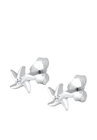 Zilveren stervormige studs met een glanzende afwerking en een kleine doorzichtige edelsteen in het midden van elke ster.