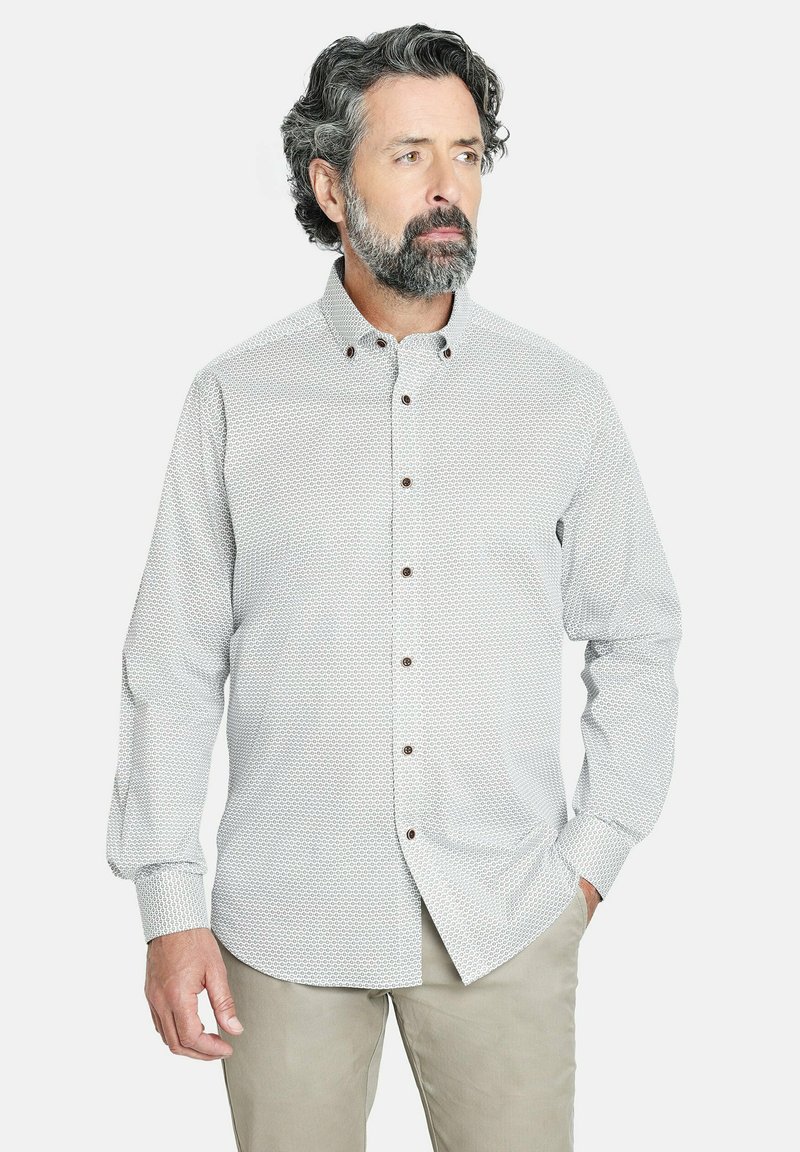 Camisa clara de botones con un patrón geométrico, botones marrones, de mangas largas y cuello estándar, combinada con pantalones beige.