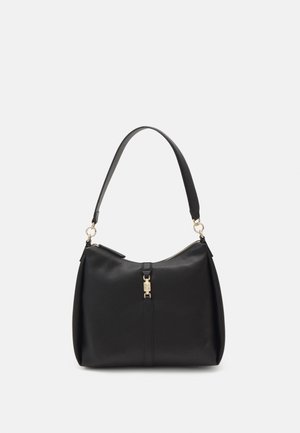 Sac en cuir noir avec une structure souple, une seule bandoulière, des accessoires en or et une fermeture à glissière. Notable pour son design minimaliste.