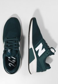 Teal athletic shoes with mesh design, white "N" logo, padded collar, and black rubber sole. Features lacing system and pull tab.