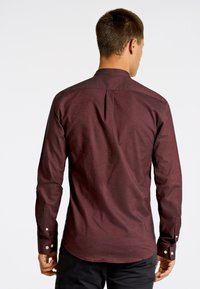 Langarmshirt in bordeauxrood, gemaakt van katoenrijke stof, met een klassieke kraag en knopenmanchetten, voorzien van een gestructureerd patroon en een rugplooidetail.