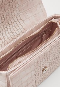 Pink faux crocodile skin handbag with textured exterior, gold zipper accents, and multiple interior compartments for organization.