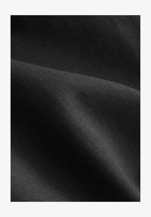 Tissu noir tissé avec une texture fine, présentant de subtiles variations de lumière. La surface semble lisse et légèrement réfléchissante.