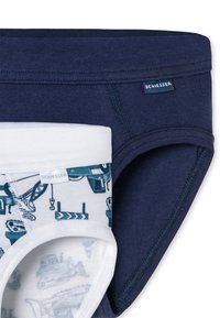 Zwei Paare Kinderunterhosen, eines in einfarbig marineblau und eines in weiß mit blauen Druckmotiven von Baufahrzeugen, beide mit Schiesser-Etiketten.