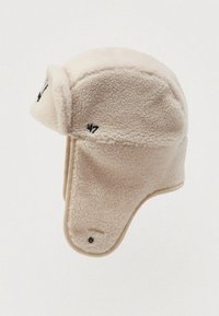 Chapeau trapper en polaire beige avec des rabats d'oreilles et logo '47' brodé en noir sur le côté.