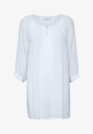Svetlomodrá, dlhá blúzka s dlhým rukávom vyrobená z pokrčeného materiálu. Má okrúhly výstrih so zapínaním na gombík a rolované manžety. Voľný strih.