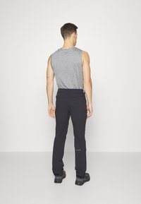 Zwarte buitenbroek met een stijlvolle, getailleerde pasvorm en duurzame stof. Een grijze mouwloze shirt is gedragen, met een eenvoudig, functioneel ontwerp.