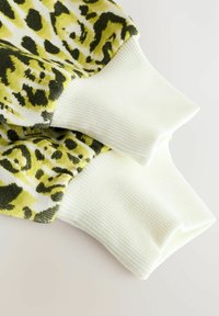 Felpa con stampa a Leopardo che presenta motivi verdi e gialli, con polsini a coste bianchi. Texture morbida, design casual e dettagli di colori a contrasto.