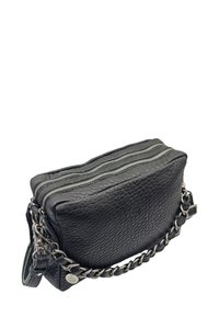 Sac en cuir noir texturé avec deux zippers en argent, une bandoulière en chaîne, et une petite étiquette métallique ronde.