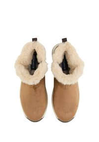 Bottines en cuir suédé marron avec une doublure et un col en fausse fourrure crème, dotées d'une semelle en caoutchouc plate et d'une languette en boucle à l'arrière.