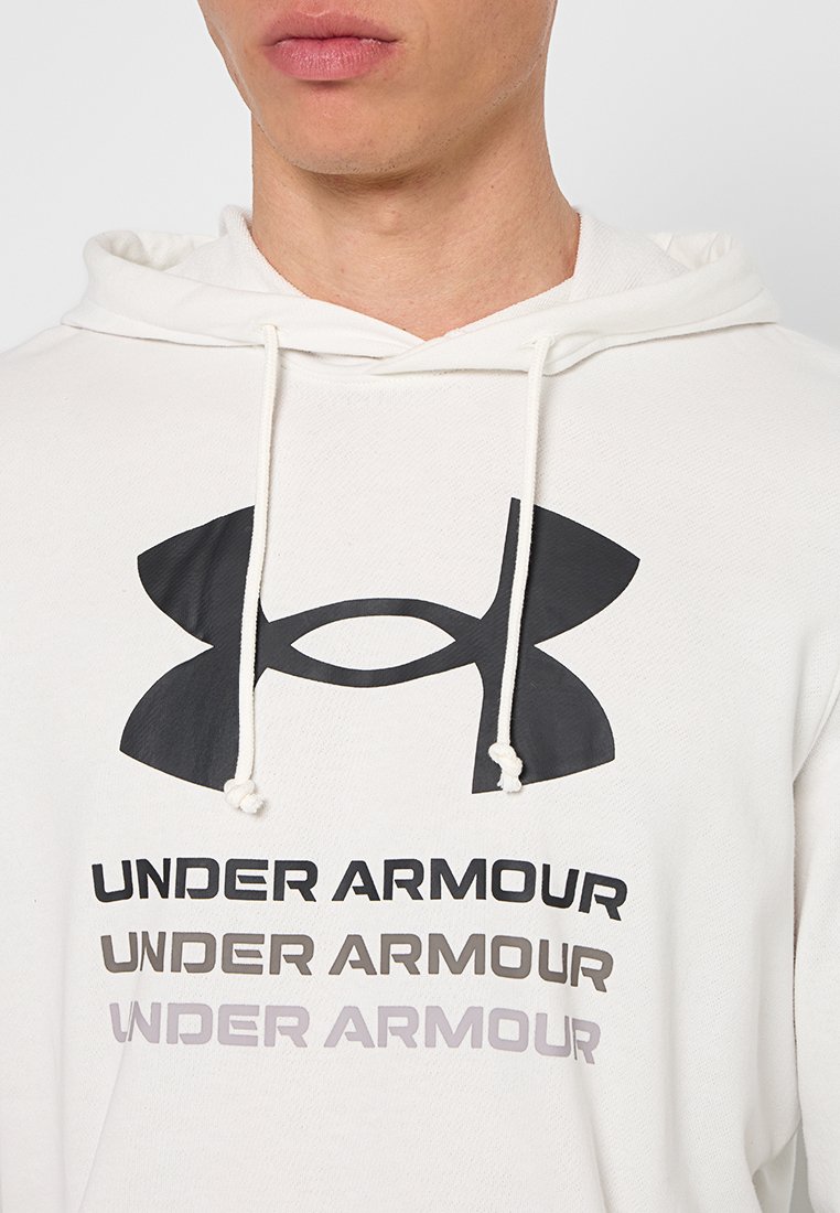 Haut à capuche blanc avec un grand logo noir d'Under Armour et un texte répété en noir, gris foncé et gris clair. Conçu avec un capuchon à cordon de serrage et une texture douce.