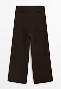 Brązowe spodnie o szerokich nogawkach z gładką fakturą, wyposażone w dwie tylne kieszenie i uszyte na miarę dla dopasowanego kroju.