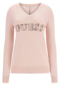 Jasnoróżowy sweter z długim rękawem, dekoltem w serek i prążkowanym dołem. Na przodzie znajduje się logo "GUESS" ozdobione kryształkami.