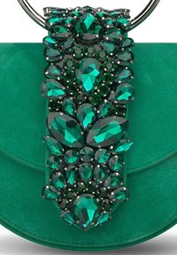 Bolso en verde esmeralda con un cierre joya que presenta varias piedras facetadas en tonos verde oscuro y transparentes, todo sobre un suave fondo de ante.