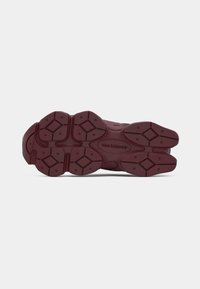 Bordeaux sneakerzool van dik rubber, met een gestructureerd patroon van diamanten en cirkels, dat grip en stabiliteit biedt.