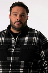 Chemise en flanelle à carreaux noir et blanc avec un col noir, fermeture à boutons sur le devant et deux poches poitrine. Tissu doux et texturé.