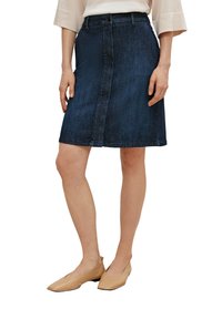 Falda de mezclilla azul oscuro con corte recto, hasta la rodilla, cierre frontal con botones y textura sutil. Combinada con zapatos planos beige.