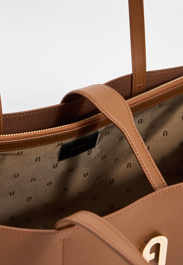 Torebka typu tote w kolorze tan z złotymi akcesoriami, gładką powierzchnią i podszewką z materiału z powtarzającym się wzorem logo. Zamek błyskawiczny.