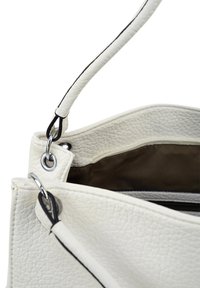White textured leather handbag with a black-accented strap, silver hardware, and an open top revealing a brown interior lining.