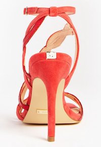 Rode suède hoge hak sandaal met kruislingse banden, open hiel en een metallic accent op de enkelband. Gladde beige zool.