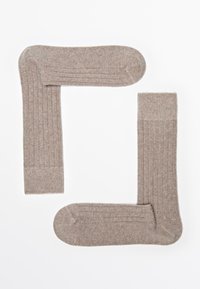 Beige gestreifte Socken, die in einer "L"-Form angeordnet sind. Sie haben eine weiche Textur, eine runde Zehenpartie und einen kontrastierenden Akzent am oberen Bund.