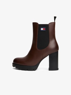 Pruuni nahast kandaga ankle-kingad mustade elastsete külgepaneelidega, ruudukujuline nina ja kõrgendatud mustriga talla; sisaldab brändi logo plaati.