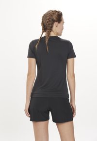 Zwart sportshirt met korte mouwen gecombineerd met zwarte shorts, die een getailleerd ontwerp en een gladde, lichte stof tonen.