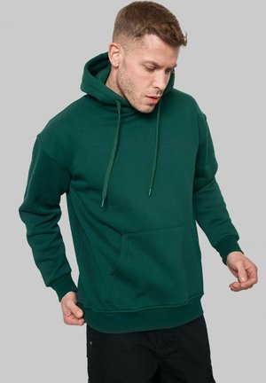 Hoodie en coton vert avec une poche avant, capuche à cordon de serrage et poignets côtelés. Texture douce et coupe décontractée.