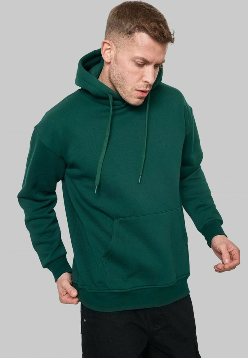 Hoodie en coton vert avec une poche avant, capuche à cordon de serrage et poignets côtelés. Texture douce et coupe décontractée.