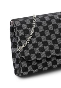 Bolso clutch en negro y gris a cuadros, hecho de tela texturizada, con una correa de cadena plateada y un cierre de solapa plegada.