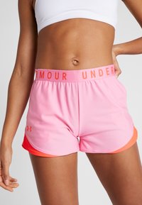 Rosa sportshorts med bred resårmidja med texten "UNDER ARMOUR" i orange. Shortsen har en lager-på-lager-design med orange kantband. Mjukt, slätt tyg.