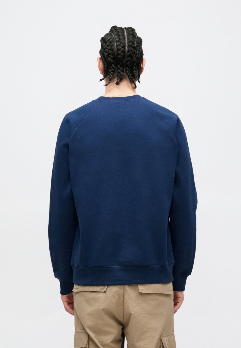 Marineblå crewneck sweatshirt med lange ærmer, lavet af et tekstureret stof. Har ribstrikkede manchetter og kant, designet til en afslappet pasform.