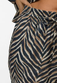 Lightweight fabric in a zebra print features a mix of dark blue, beige, and brown. The waistband is elastic with a tie detail.