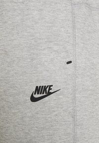 Sweatshirt cinza em algodão com um logo da Nike preto, textura suave e detalhe de costura lateral. Não há elementos visuais adicionais presentes.