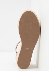 Semelle de chaussure marron clair avec une prise en caoutchouc texturée et un détail en fibre naturelle le long du bord. Taille 37 marquée près du talon.