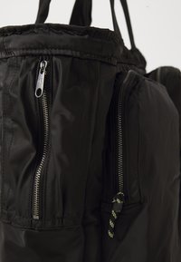 Black nylon backpack featuring a padded design, dual zippered compartments, textured accents, and sturdy fabric straps.