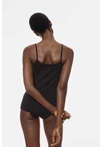 Zwarte, aansluitende camisole met dunne bandjes, een gladde textuur en een rechte zoom, gedragen met bijpassende shorts, gezien van achteren.