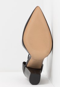 Černá dámská obuv na vysokém podpatku s špičatou špičkou. Hladký kožený svršek, gumová podrážka a blokový podpatek. Texturovaná spodní část s drážkami.