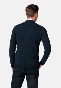 Tmavě modrý pletený svetr s texturovaným vzorem, přiléhavého střihu, s dlouhými rukávy a žebrovanými manžetami a spodním lemem, zobrazený zezadu.